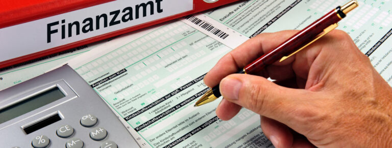 Hand mit Stift, füllt Steuerformular aus, Ordner mit "Finanzamt", Taschenrechner daneben.
